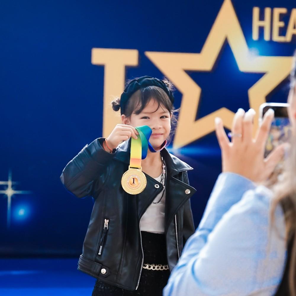 Student proudly holding a first place medal on stage at Heathfield's Got Talent.