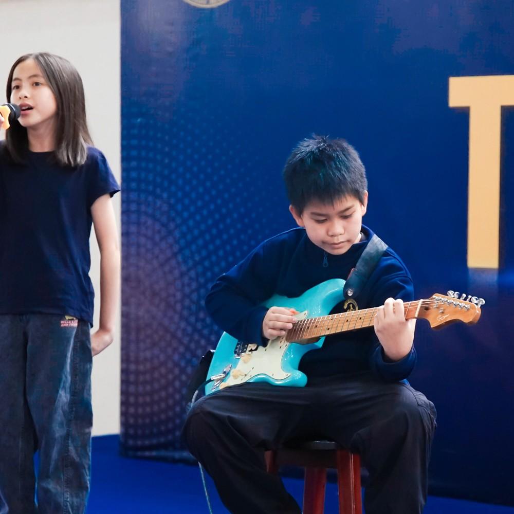 Talented musician plays the electric guitar while another student sings.