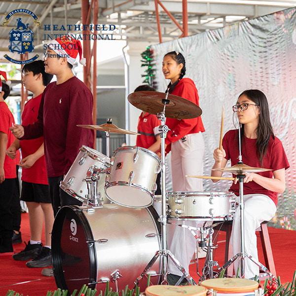 A group of students performs a musical piece, with one playing the drums, as part of the festive Christmas show.