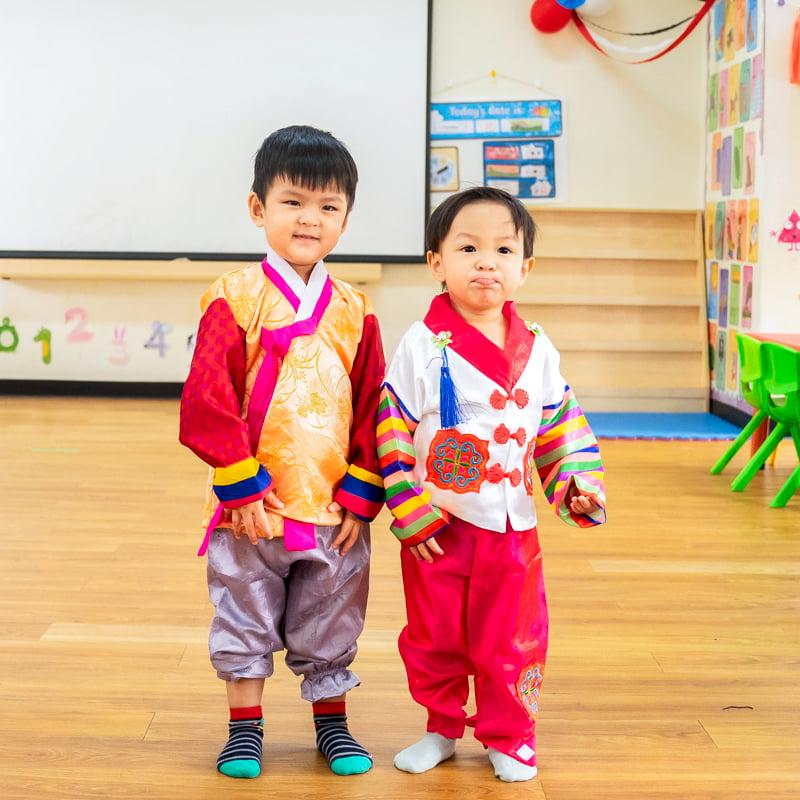 Two boys in colorful traditional Korean outfits posing for a photo.