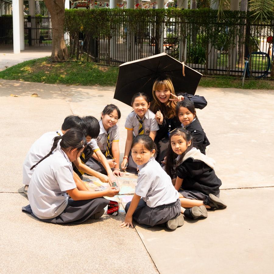 Students posing with teacher while working on their chalk art