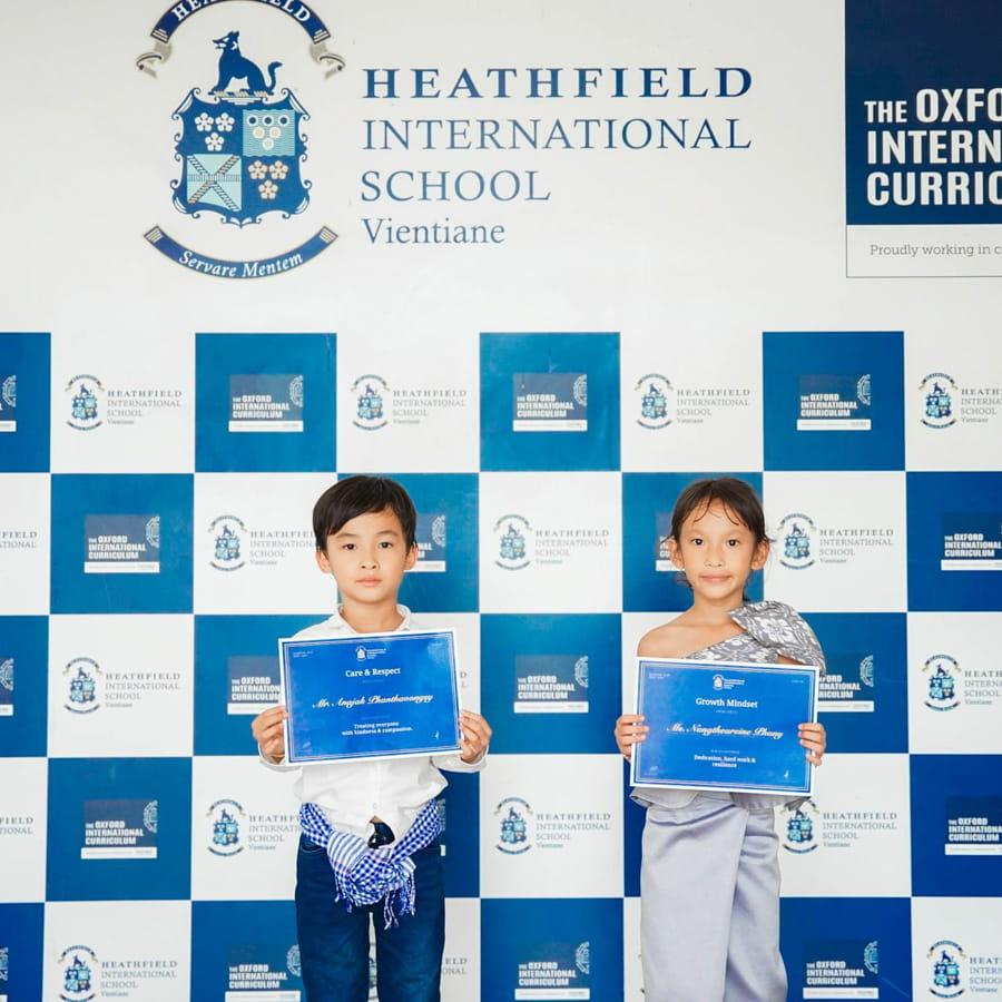 Two students smiling and holding achievement certificates
