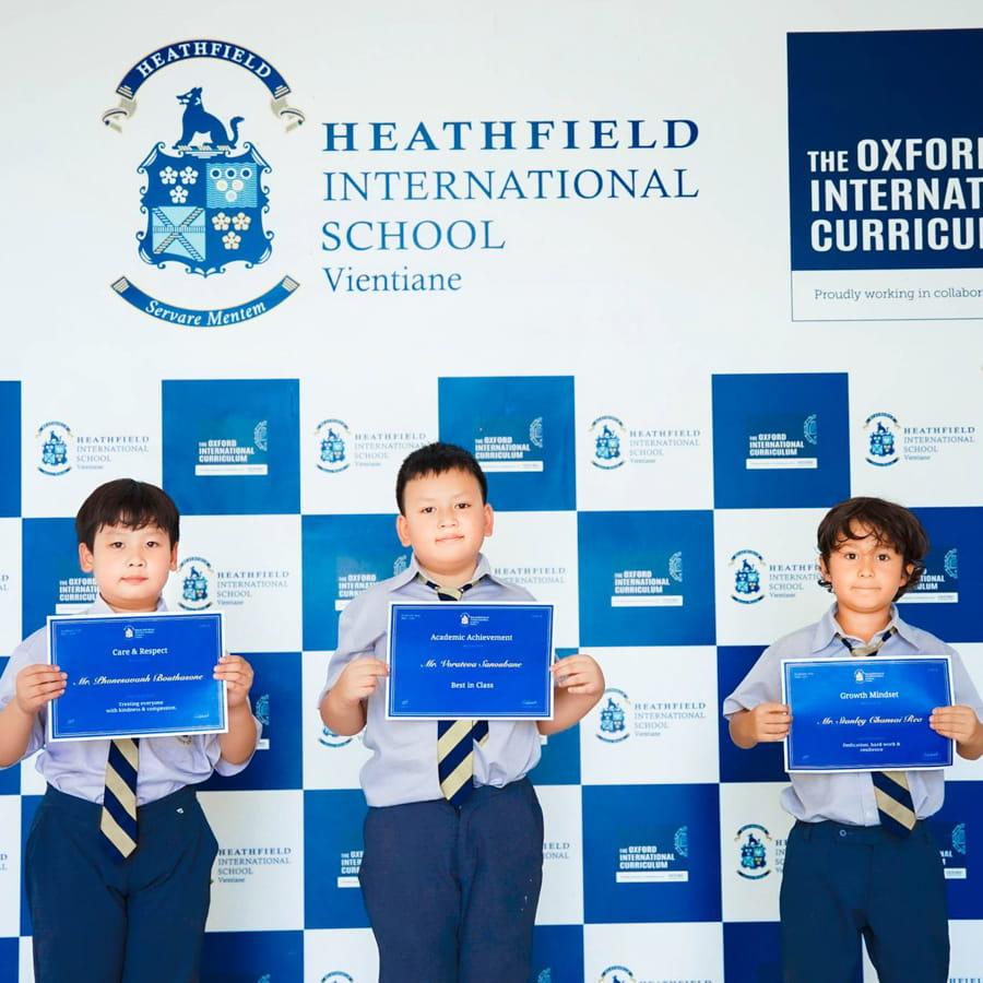 Three students smiling and holding achievement certificates
