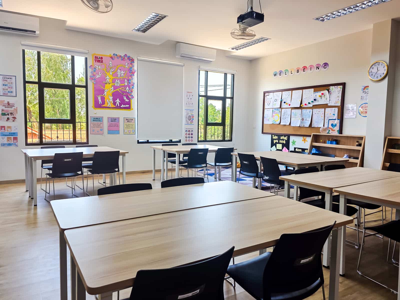 A spacious classroom designed for global skills learning, featuring large windows, bulletin boards with student work, and neatly arranged tables and chairs.