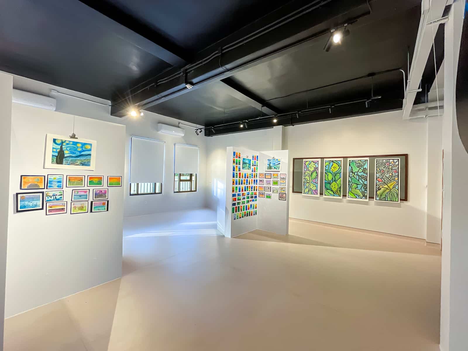 A modern art gallery space displaying vibrant student artwork, with spotlights illuminating the area.